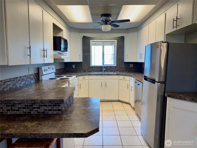 a kitchen with stainless steel appliances granite countertop a sink a stove top oven a refrigerator a counter top space and cabinets