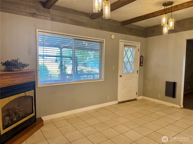 a view of an empty room with wooden floor and a fireplace