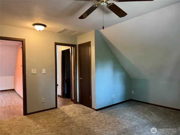 an empty room with closet and a chandelier fan