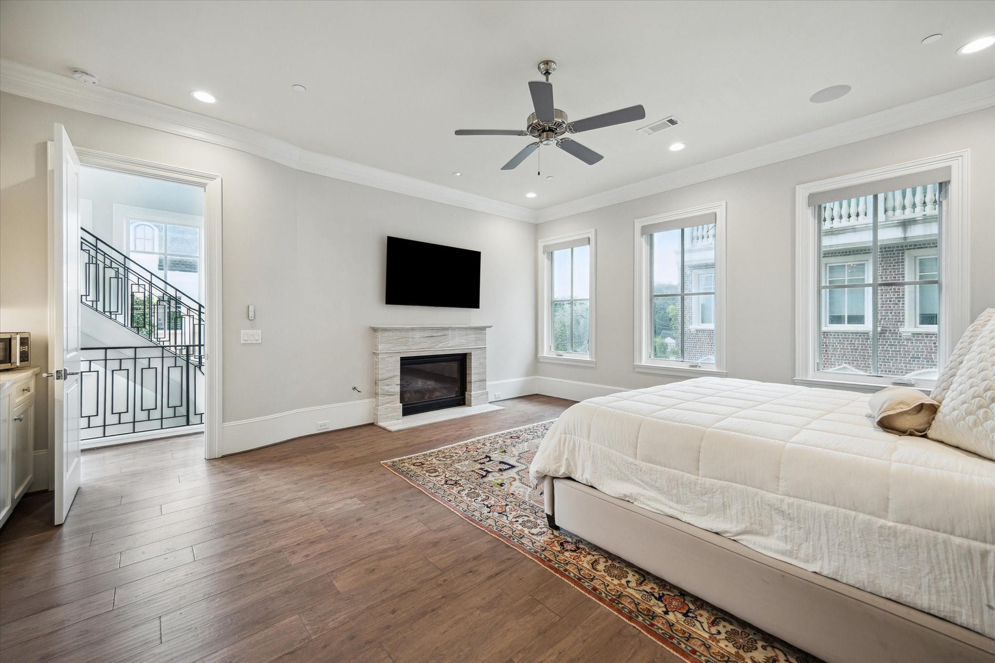 2336 Welch Street Houston, TX 77019 - Photo 26 of 39 a spacious bedroom with a large bed a flat tv screen and a fireplace