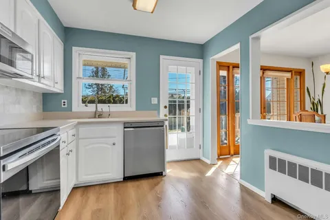 a kitchen with stainless steel appliances white cabinets and wooden floors