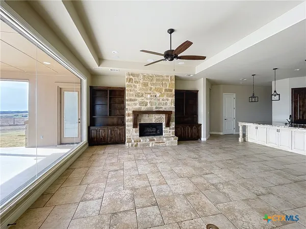 a view of a livingroom with a fireplace a ceiling fan and windows