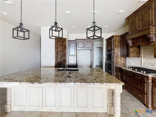 a kitchen with kitchen island granite countertop a stove a sink a refrigerator and wooden cabinets