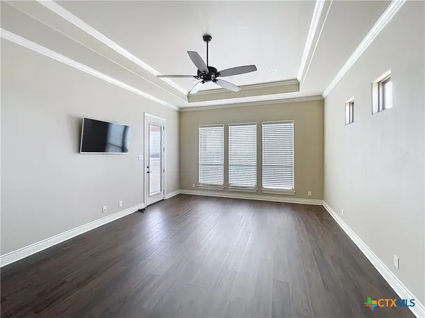 an empty room with wooden floor chandelier fan and windows