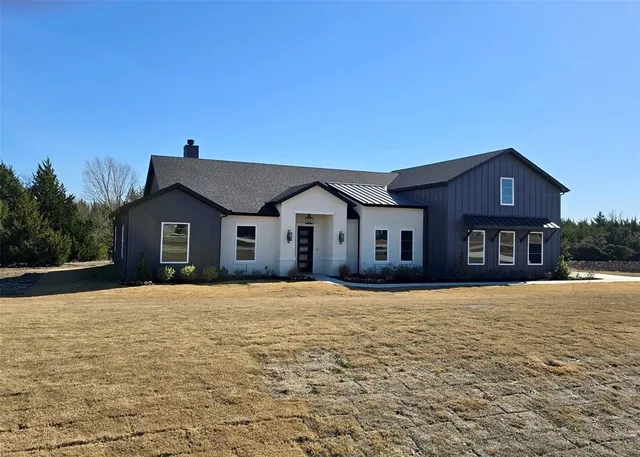 a front view of house with yard and trees in the background