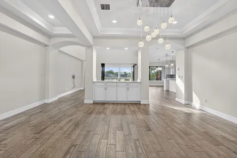 an empty room with wooden floor ceiling fan and windows