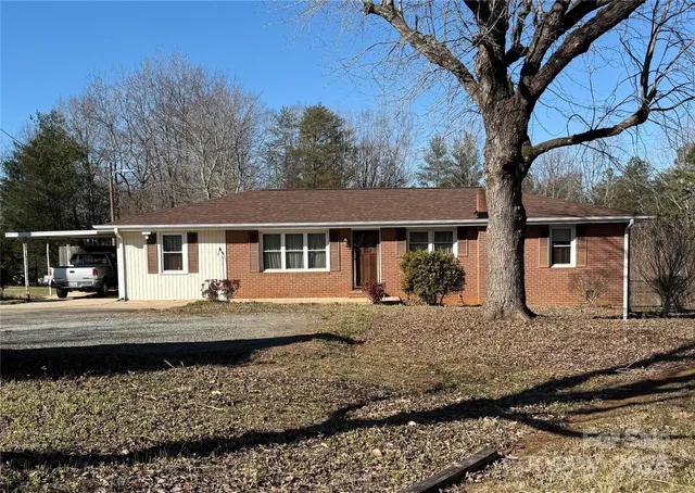 a view of a house with a large tree next to a yard