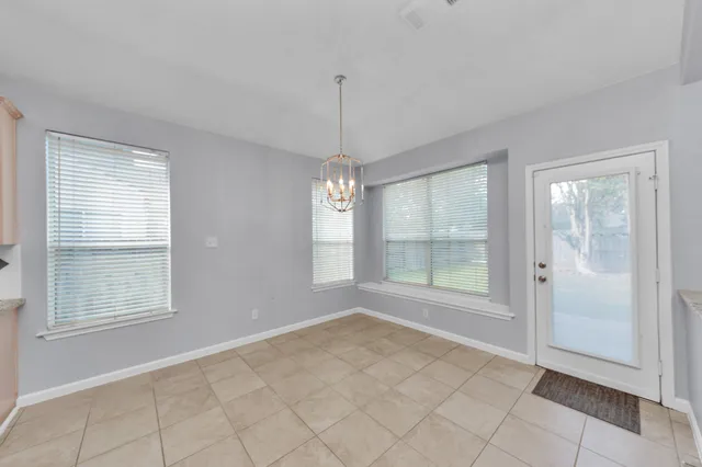 an empty room with windows and chandelier