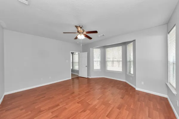 a view of an empty room with a window and a kitchen