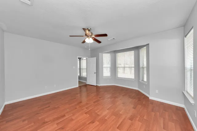 a view of an empty room with a window and a kitchen