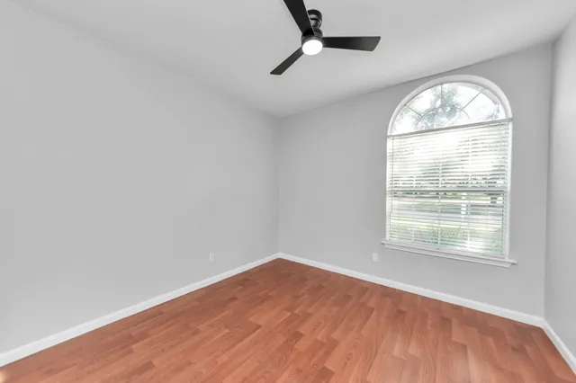 an empty room with wooden floor exposed radiator and windows