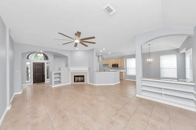 a view of a livingroom with a ceiling fan a fireplace and windows