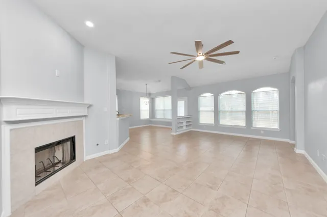 a view of an empty room with chandelier fan and a fireplace