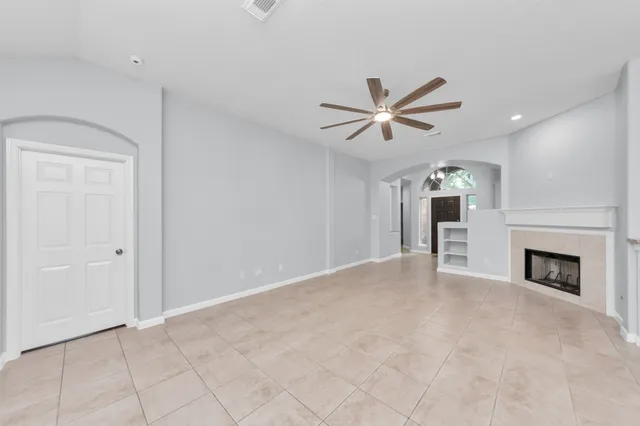 a view of an empty room with kitchen view and a fireplace