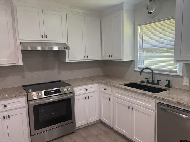 a kitchen with granite countertop white cabinets and a stove top oven