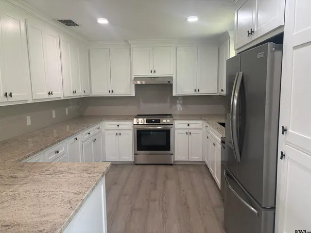 a kitchen with granite countertop white cabinets and stainless steel appliances