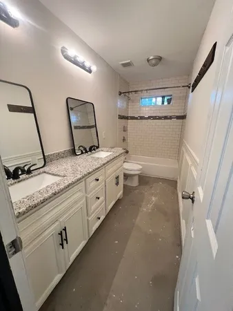 a bathroom with a granite countertop sink mirror and toilet