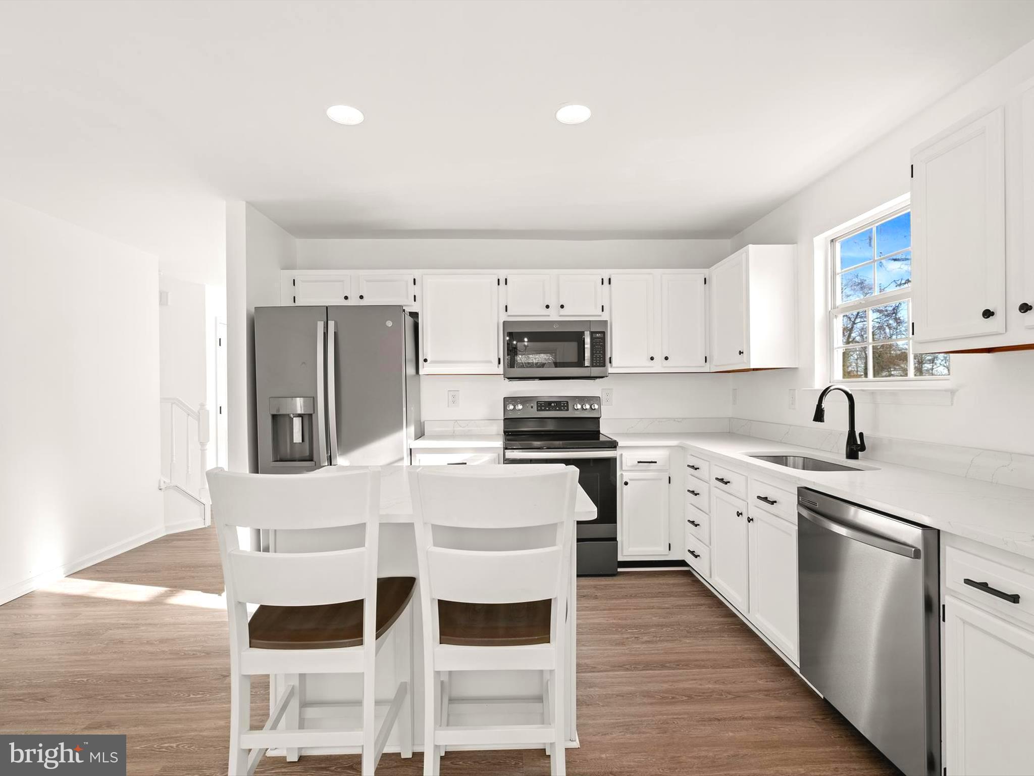 a kitchen with stainless steel appliances a stove top oven a sink refrigerator and white cabinets