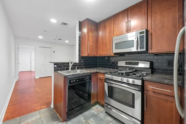 a kitchen with stainless steel appliances granite countertop wooden cabinets stove top oven and sink
