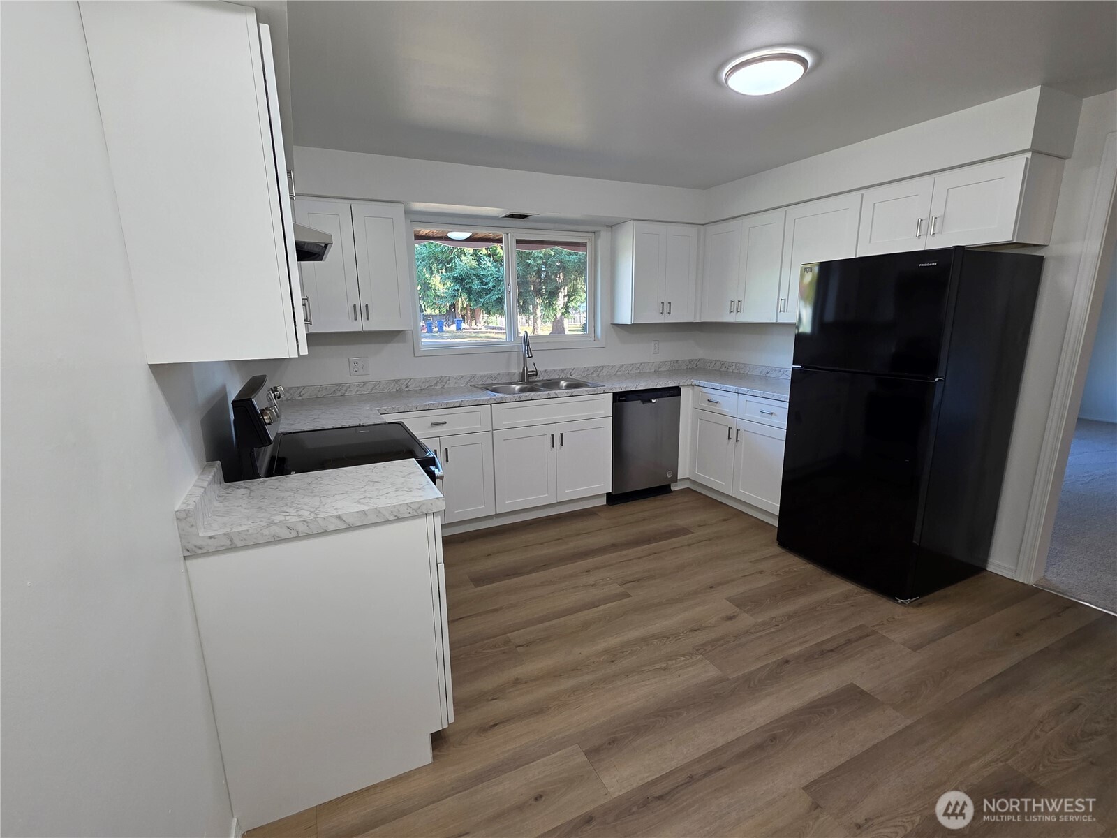 620 North Street Monroe, WA 98272 - Photo 28 of 38 a kitchen with a refrigerator a stove top oven a sink and dishwasher with wooden floor