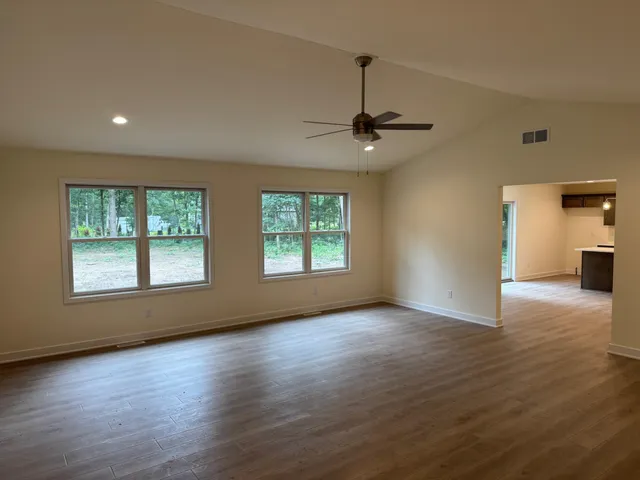 an empty room with wooden floor chandelier and windows