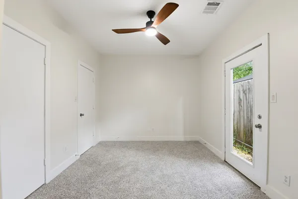 an empty room with a ceiling fan and glass door