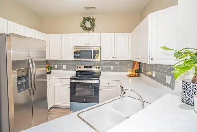 a kitchen with stainless steel appliances a stove a sink a microwave a refrigerator and cabinets