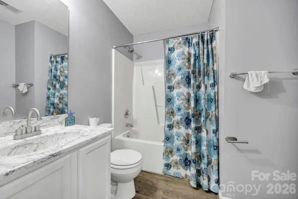 a bathroom with a granite countertop sink a toilet and shower curtain
