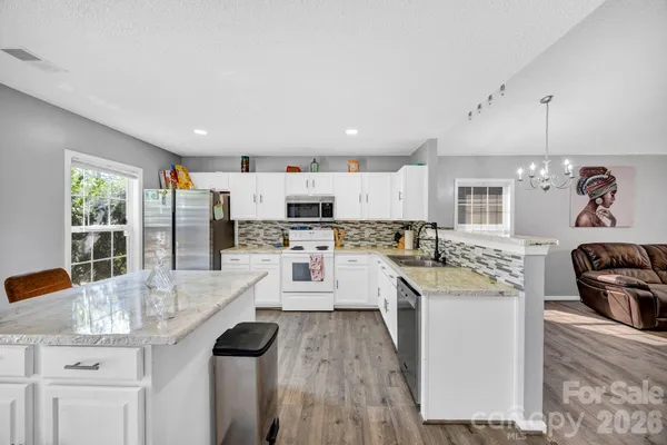a kitchen with stainless steel appliances kitchen island granite countertop a stove and white cabinets