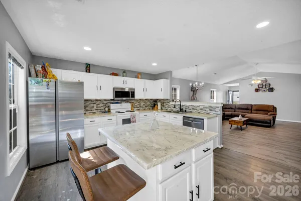 a kitchen with stainless steel appliances granite countertop a refrigerator and a stove top oven