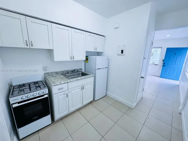 a kitchen with granite countertop white cabinets and stainless steel appliances