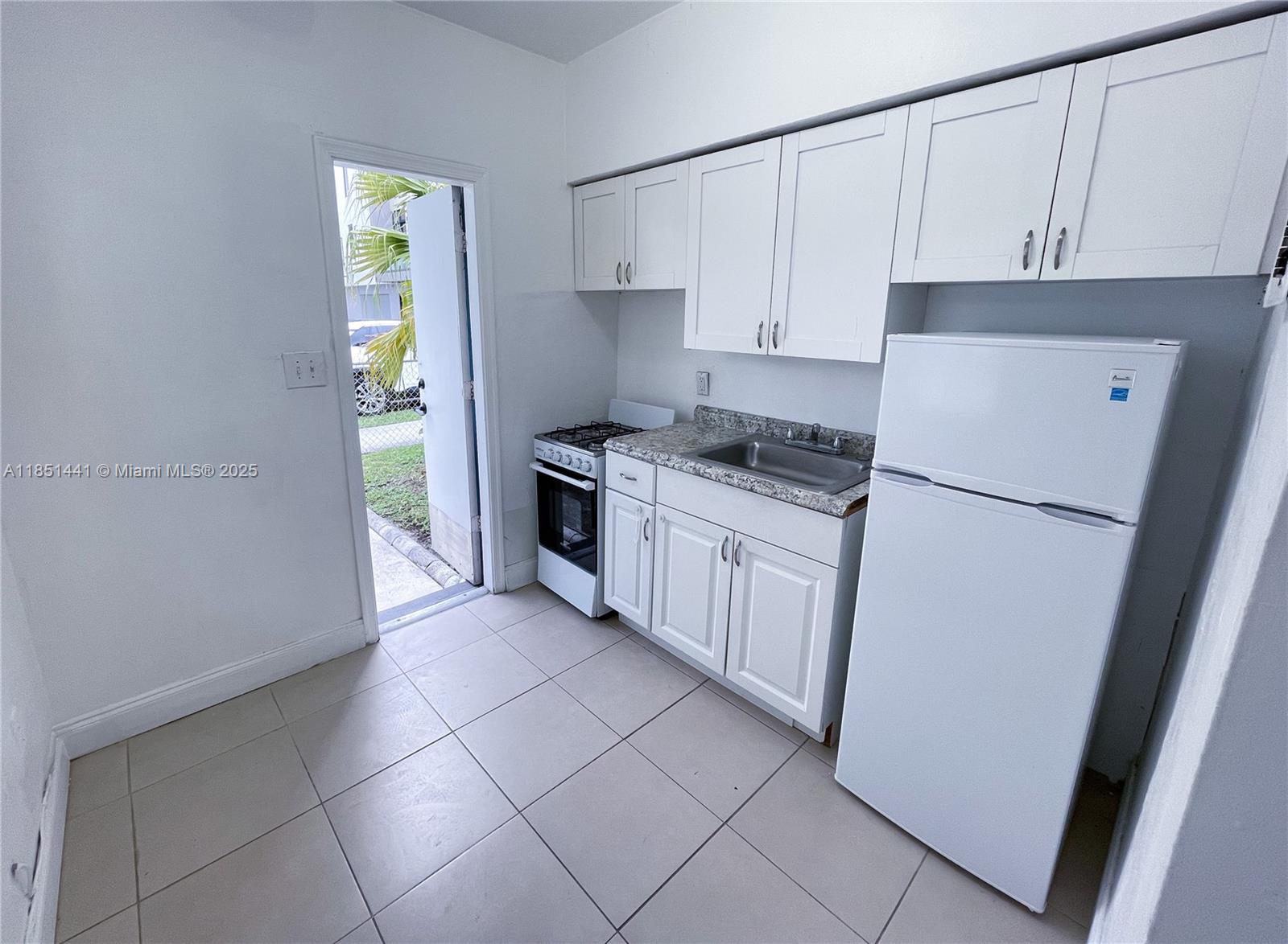2499 Southwest 27th Street, Unit 9 Miami, FL 33133 - Photo 7 of 19 a kitchen with stainless steel appliances granite countertop a refrigerator sink and white cabinets