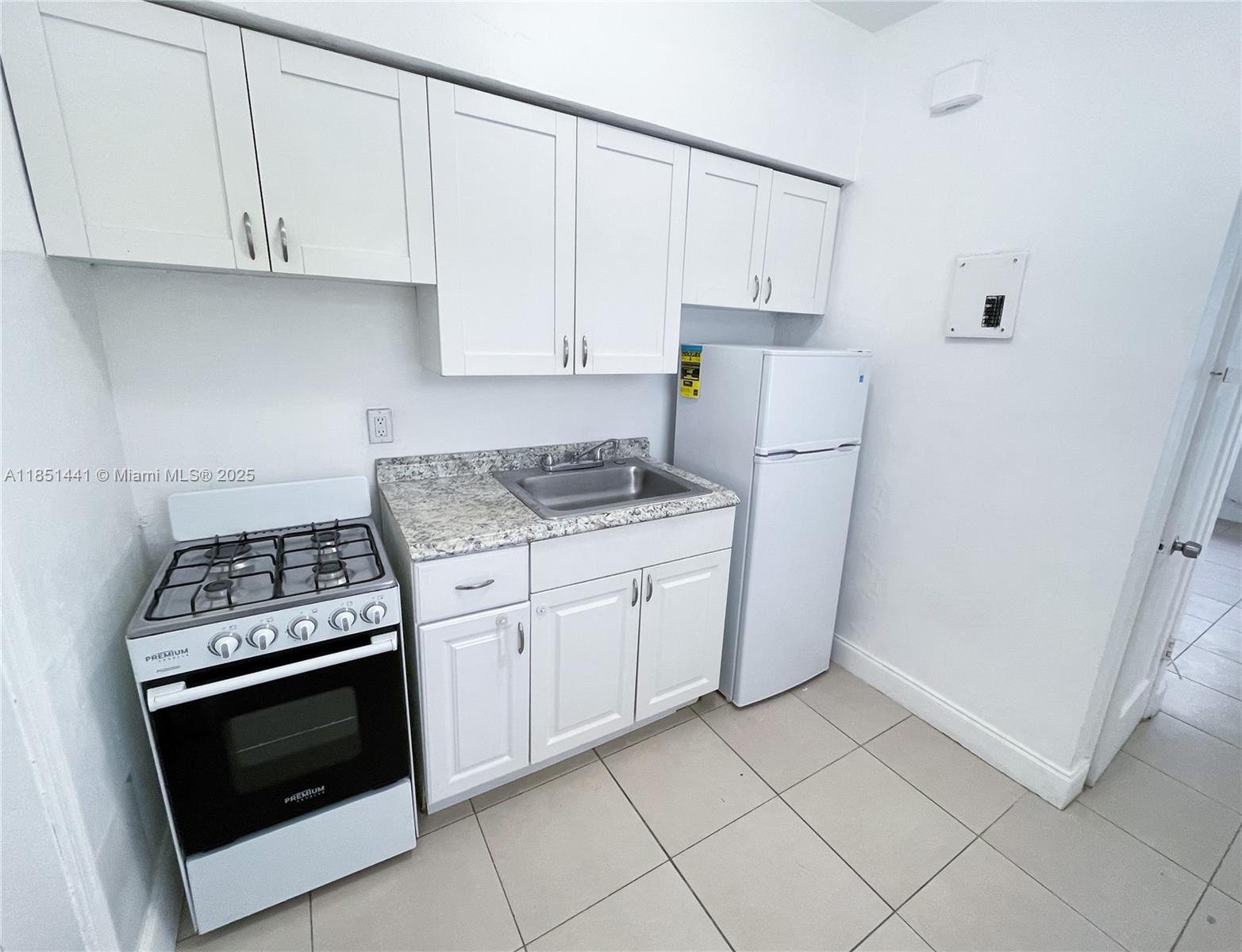 2499 Southwest 27th Street, Unit 9 Miami, FL 33133 - Photo 8 of 19 a kitchen with granite countertop white cabinets and white appliances