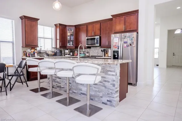 a kitchen with stainless steel appliances granite countertop a stove a refrigerator a sink a dining table and chairs