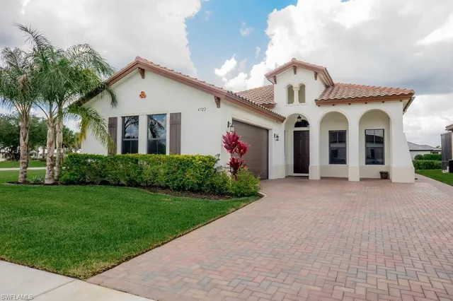 a view of a white house with a big yard and potted plants