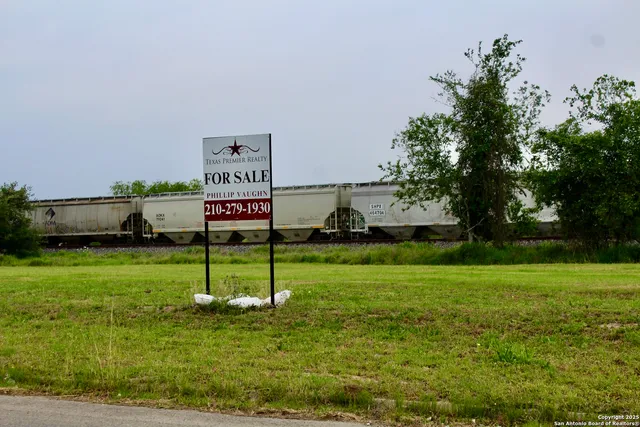a sign that is sitting in the grass near a tree