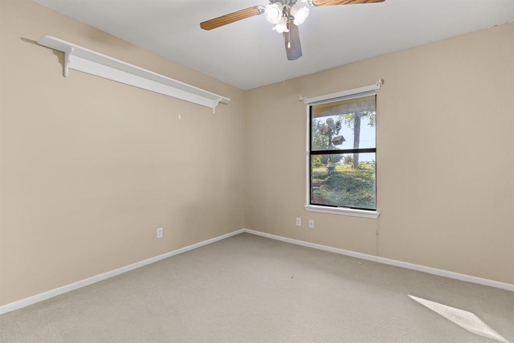 13539 Chapel Road Lorena, TX 76655 - Photo 20 of 37 Carpeted room featuring a single window with outdoor scenery, neutral wall paint, white baseboards, and a ceiling fan with light fixture