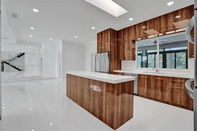 a kitchen with stainless steel appliances a kitchen island wooden cabinets and entryway