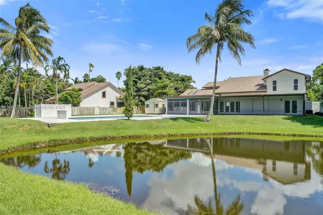 a view of swimming pool with a yard and palm trees