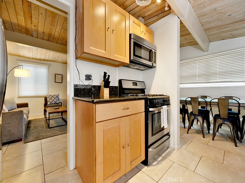 129 45th Street Newport Beach, CA 92663 - Photo 11 of 38 a kitchen with stainless steel appliances granite countertop a refrigerator a stove top oven a sink a dining table and chairs with wooden floor
