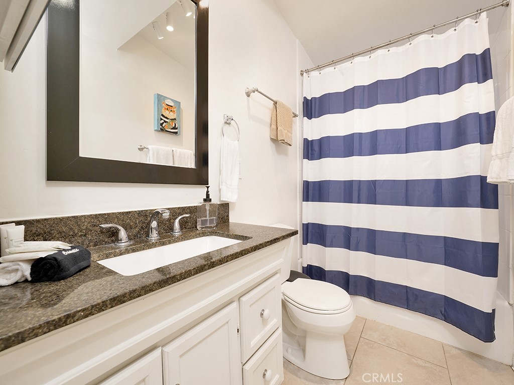 129 45th Street Newport Beach, CA 92663 - Photo 14 of 38 a bathroom with a granite countertop toilet a sink and a mirror