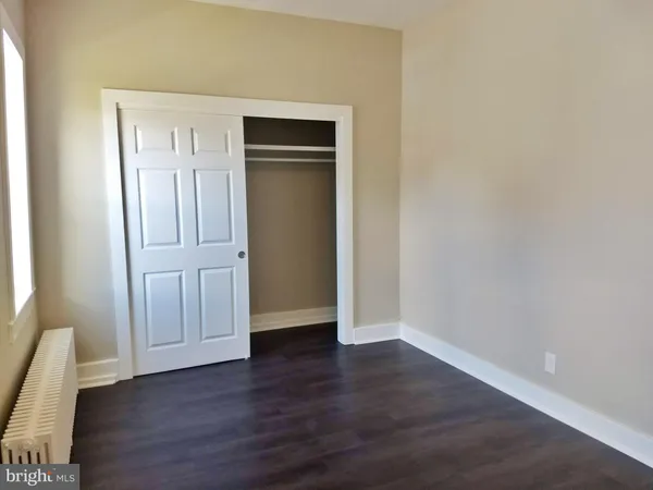 a view of an empty room with wooden floor and closet