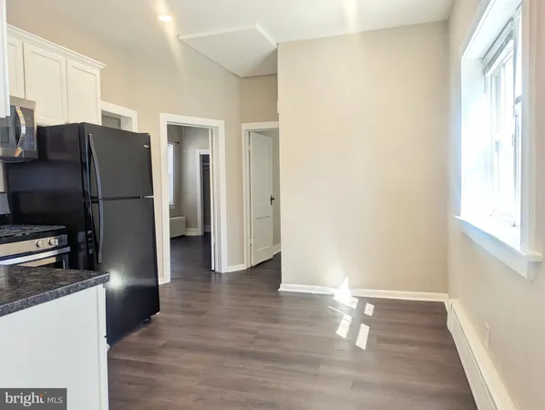 a view of a kitchen with a refrigerator a ceiling fan and wooden floor