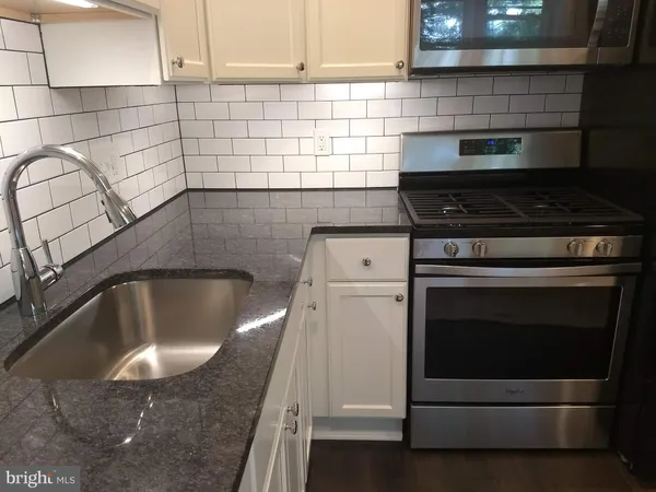 a kitchen with granite countertop a stove sink and cabinets