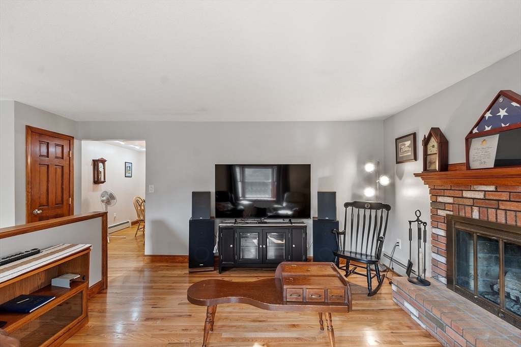 622 Townsend Road Groton, MA 01450 - Photo 6 of 39 a living room with furniture a flat screen tv and a fireplace