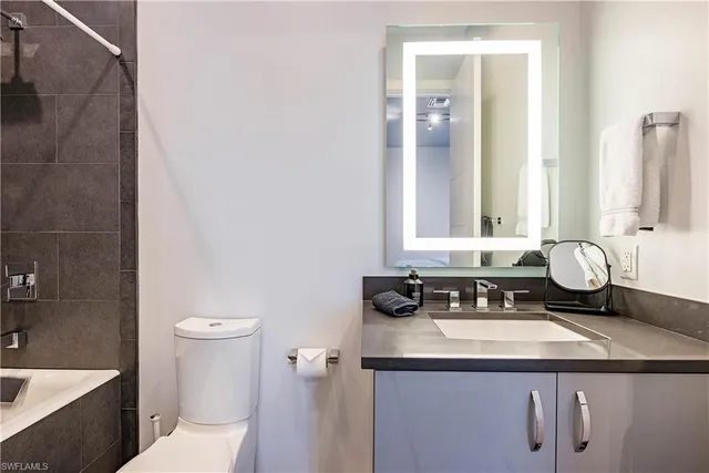 a bathroom with a granite countertop sink a toilet and a mirror