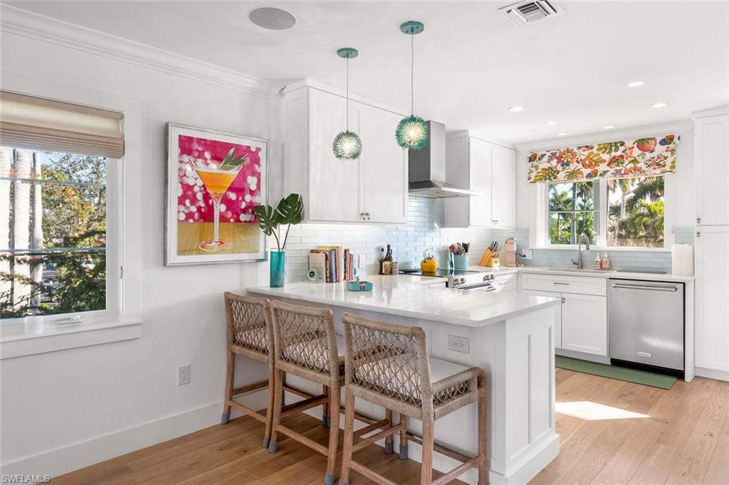 320 14th Avenue South, Unit 320B Naples, FL 34102 - Photo 3 of 14 a room with stainless steel appliances kitchen island granite countertop a stove a sink and white cabinets with wooden floor