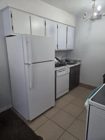 a white refrigerator freezer and a stove sitting inside of a kitchen
