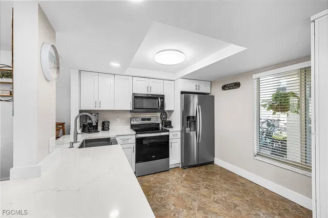 a kitchen with stainless steel appliances granite countertop a stove a sink dishwasher a refrigerator and a microwave oven with white cabinets