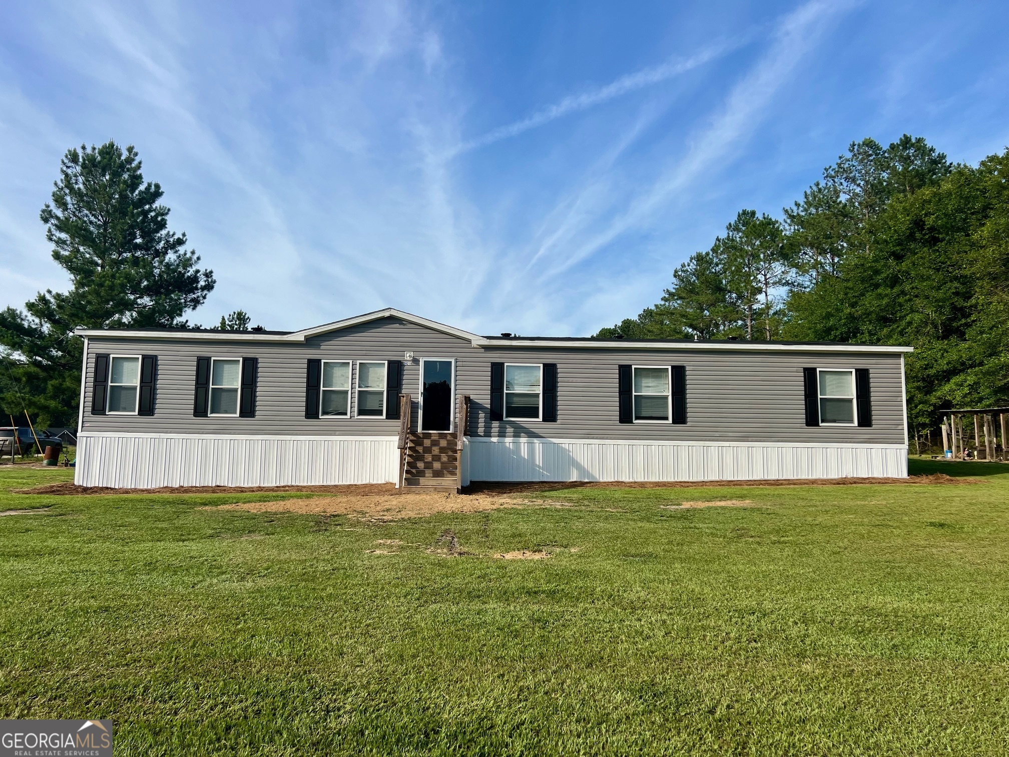 a front view of house with yard and trees in the background